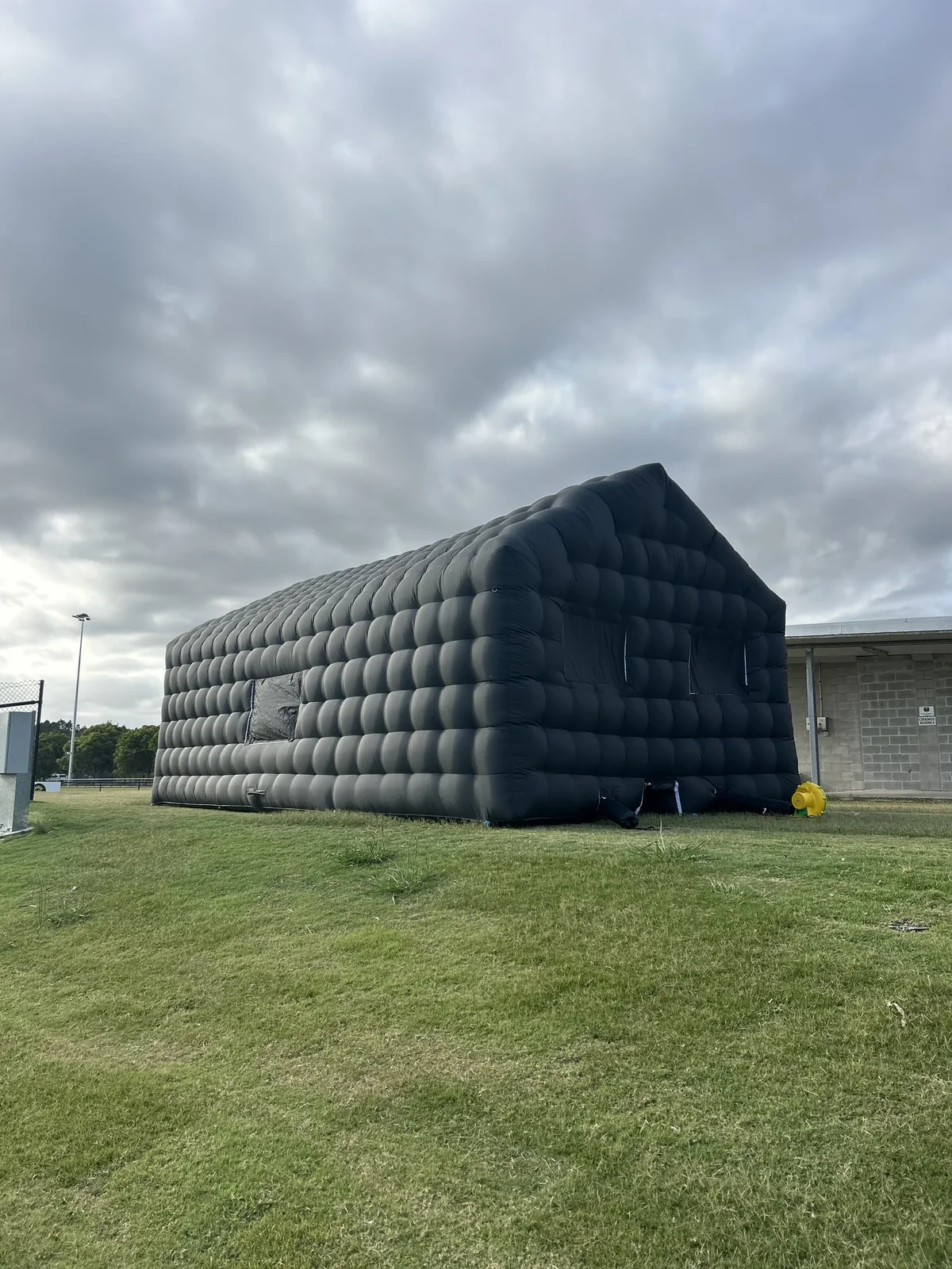 Front and side of Cove Events black inflatable nightclub set up on a flat lawn in daylight