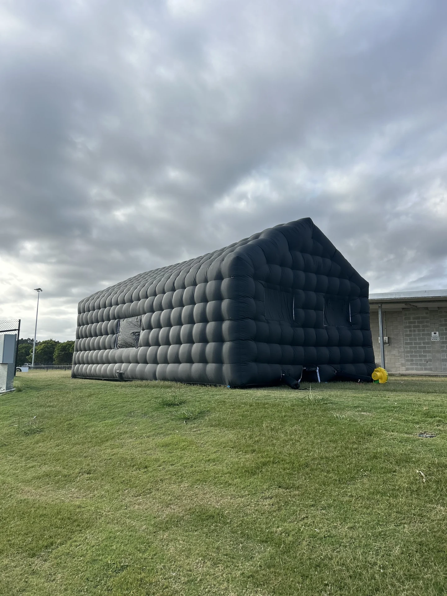 Front and side view of the black inflatable nightclub on a grass field