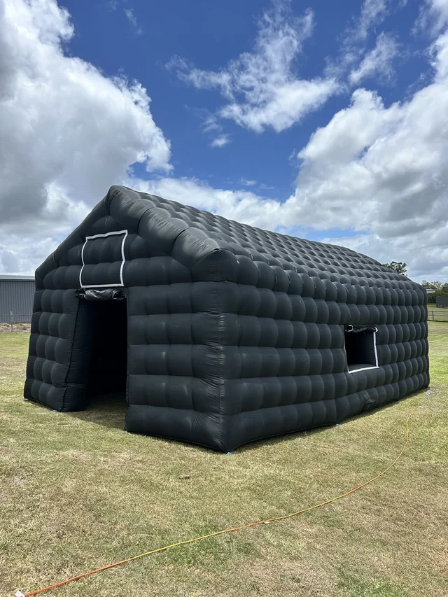 Front and side of Cove’s black inflatable nightclub set up on grass in daylight