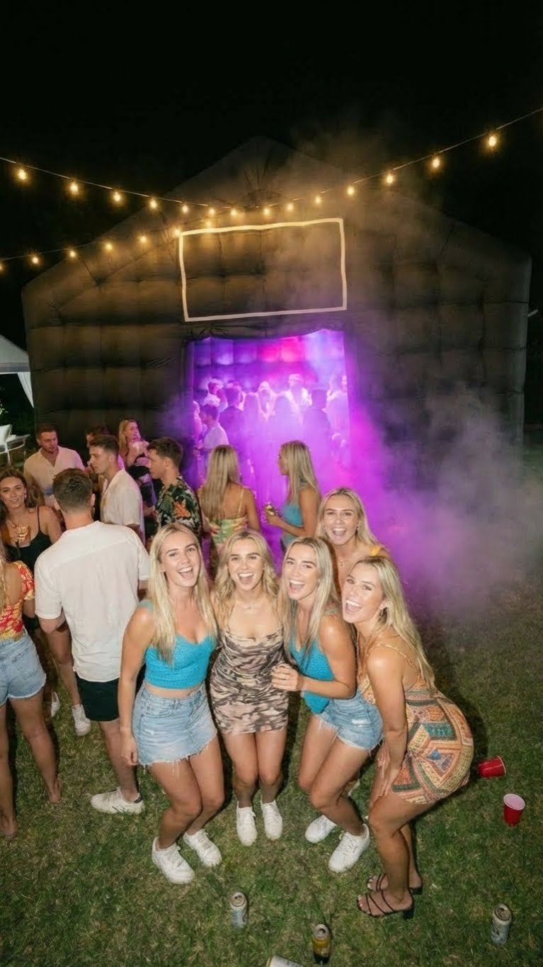 Party guests outside the inflatable nightclub beneath festoon lights at night