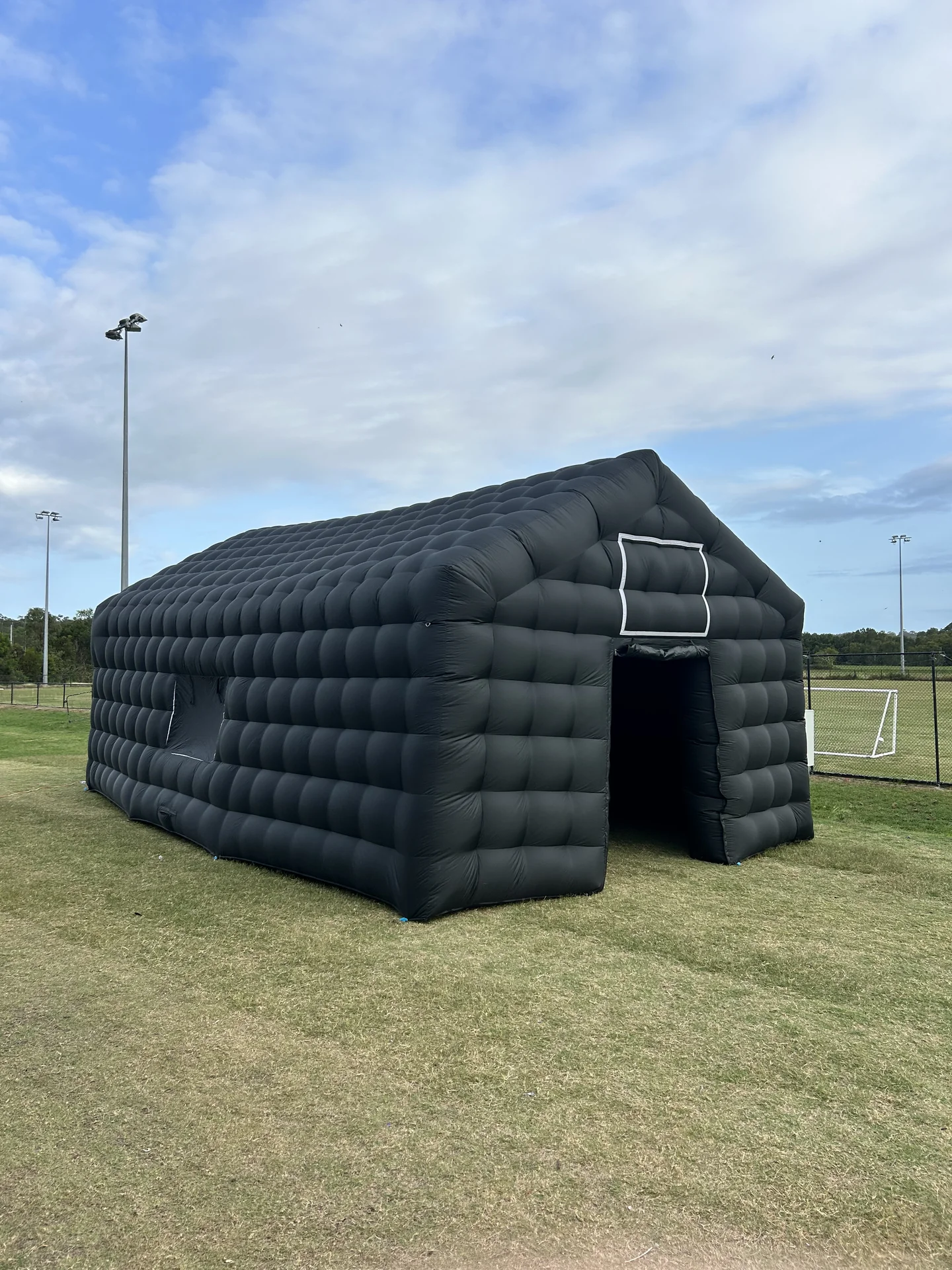 Side view of the black inflatable nightclub with its entrance open on grass