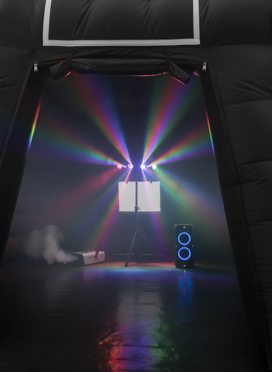 Multicoloured party lights and haze inside a black inflatable nightclub