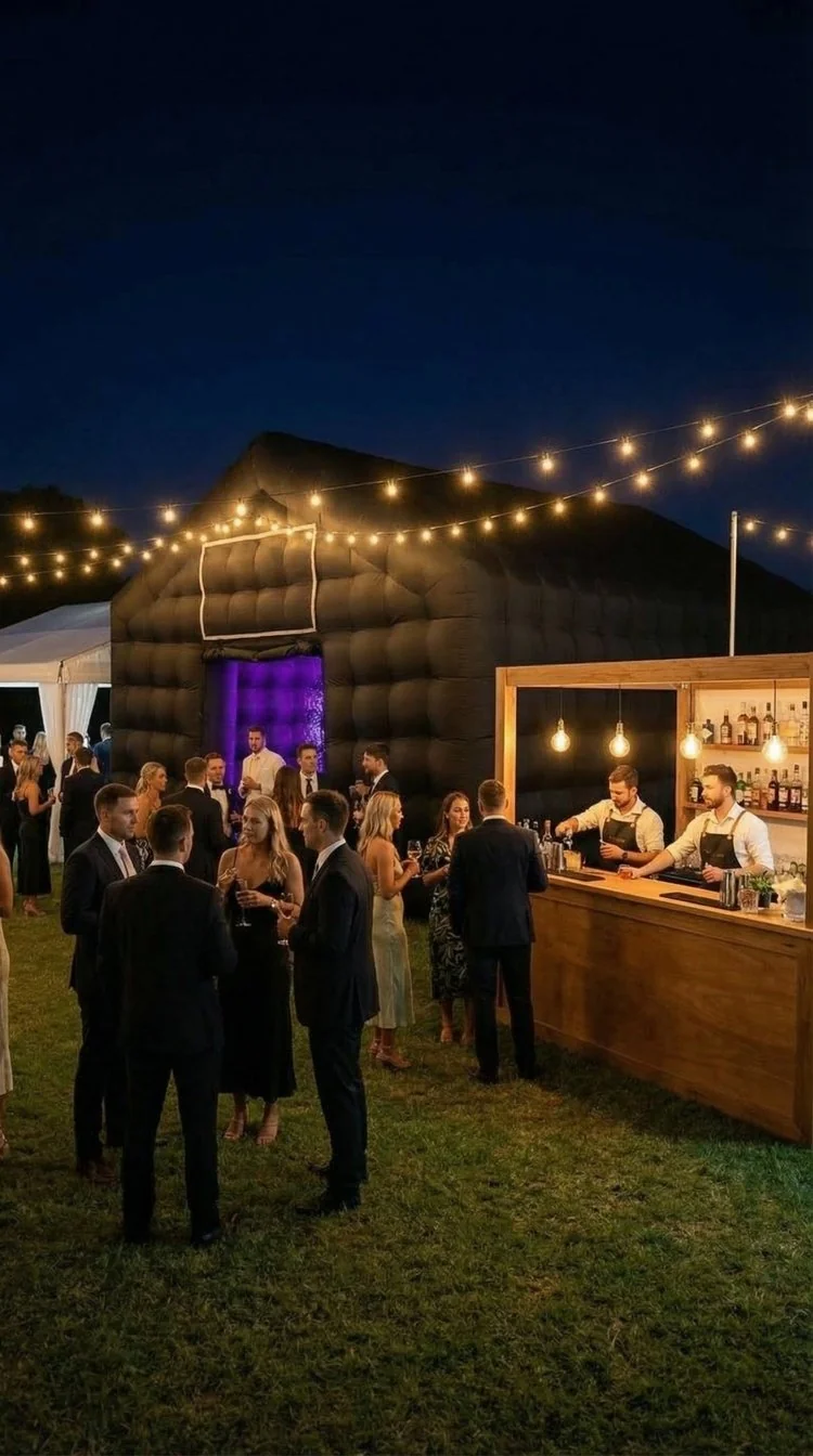 Guests outside a black inflatable nightclub with festoon lights at night