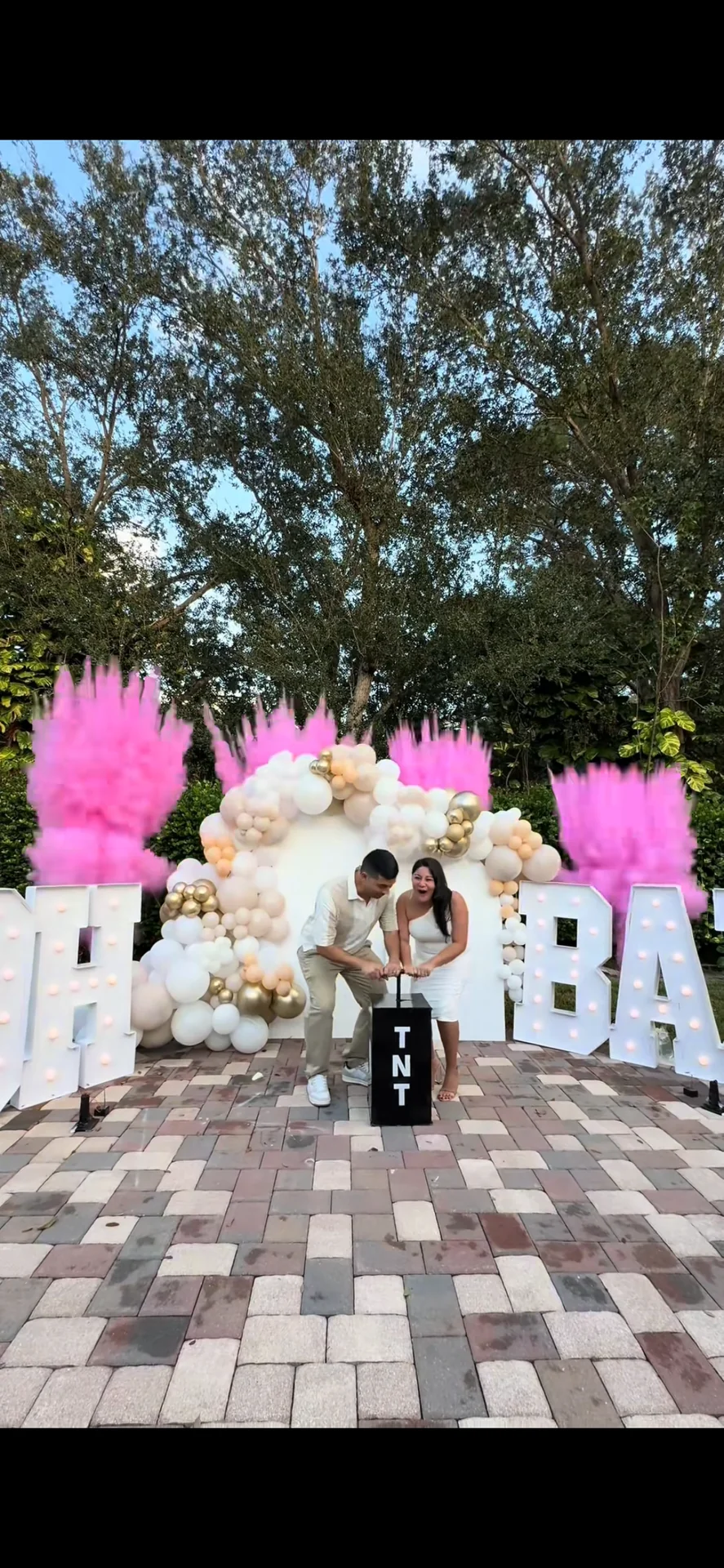 Outdoor gender reveal display with balloons, BABY letters and a TNT box